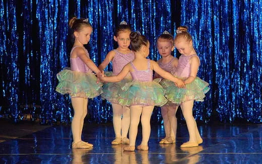 a group of girls in dresses on a stage
