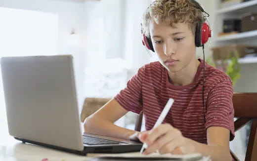 a young boy wearing headphones and using a laptop