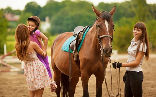 a couple of girls walking next to a horse