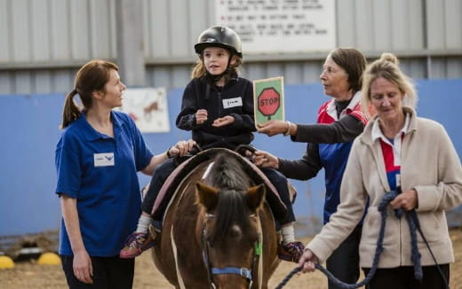 a group of people standing around a girl on a horse