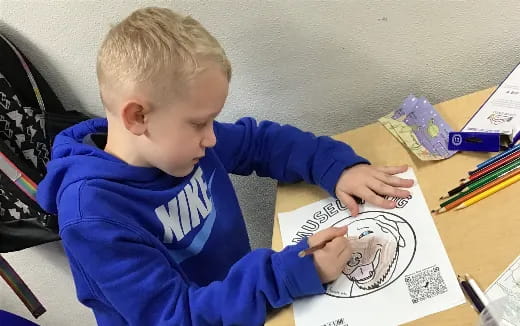 a child sitting at a desk writing on a book