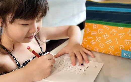 a young girl writing on a piece of paper