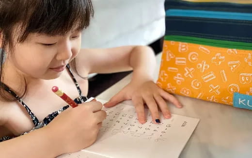 a young girl writing on a piece of paper