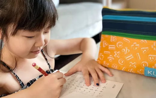 a young girl writing on a piece of paper