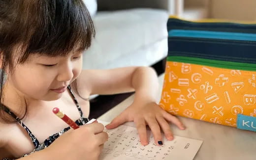 a young girl writing on a piece of paper