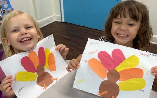 a couple of children smiling and holding up a book