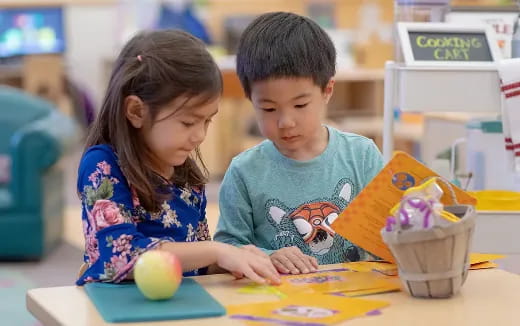 a young girl and a young boy looking at a book
