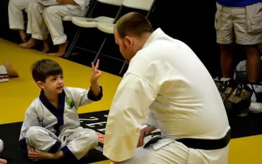 a person and a boy sitting on a yellow mat