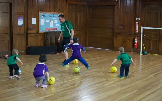 a person and kids playing with football balls