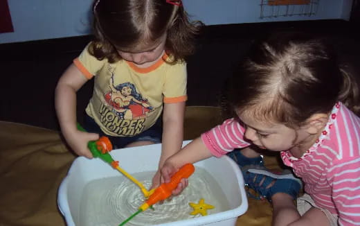 a couple of young girls playing with a toy