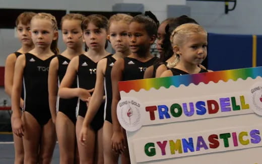 a group of girls in swimsuits holding a sign