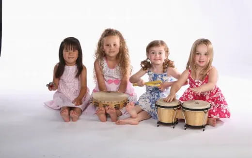 a group of girls sitting on the floor with drums
