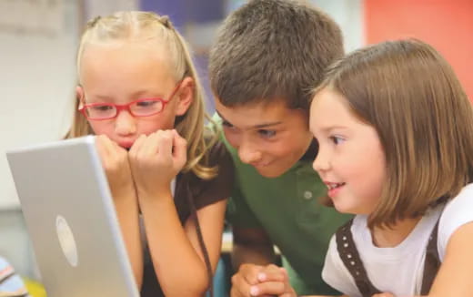 a group of children looking at a laptop