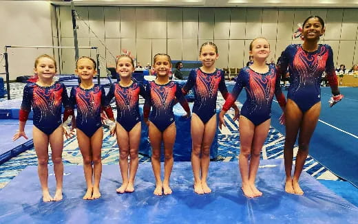 a group of girls in swimsuits standing on a blue mat