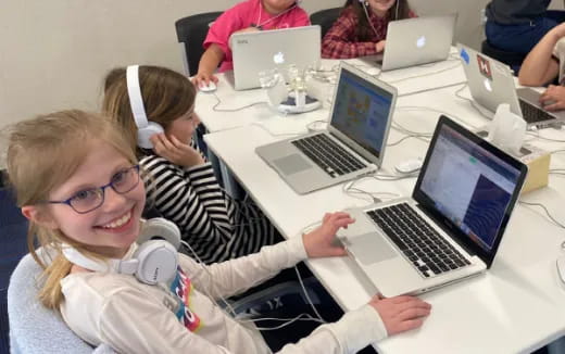 a group of people sitting at a table with laptops