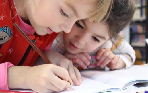 a young girl and a young boy looking at a book