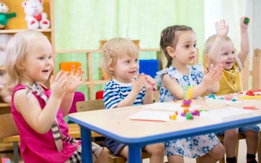 a group of children sitting at a table with candles
