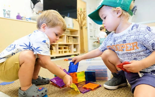 a couple of young boys playing with toys on the floor
