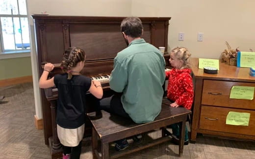 a person and a couple of children playing a piano