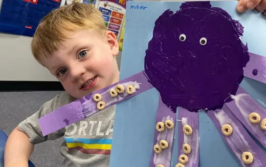 a boy smiling next to a toy