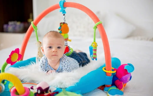 a baby in a basket with colorful toys