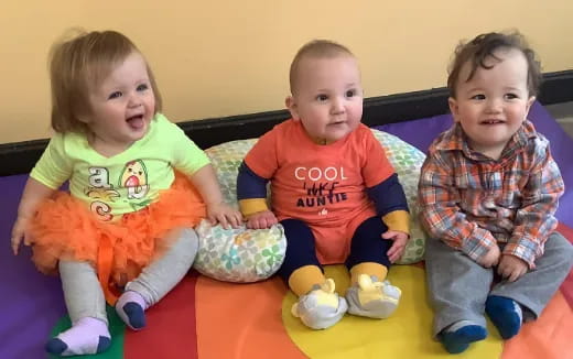 a group of children sitting on a yellow mat