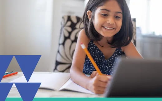 a young girl smiling while writing on a piece of paper