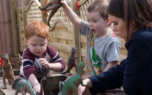 a person and two children petting a group of birds