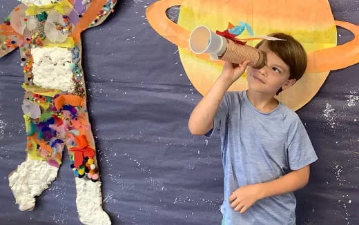 a child standing next to a painting