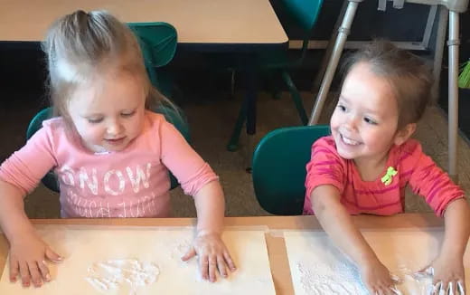a couple of young girls sitting at a table