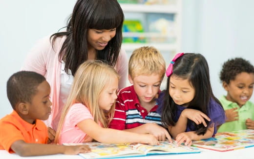 a person and several children looking at a book