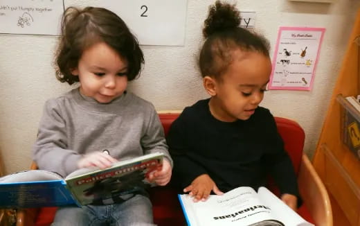 a couple of children reading a book