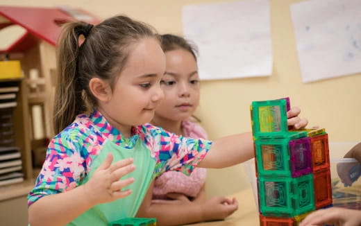 a couple of young girls playing with a toy