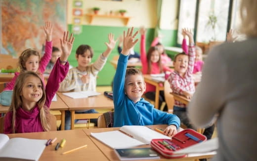 a group of children raising their hands
