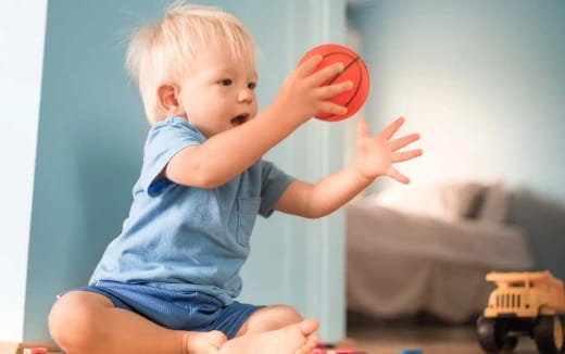a baby holding a red ball