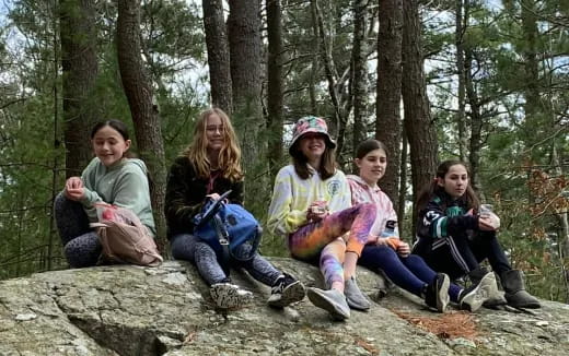 a group of people sitting on a rock in the woods