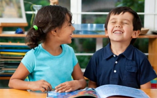 a young girl and a young boy reading a book