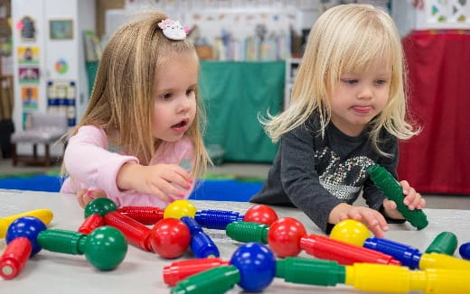 a couple of young girls playing with toys on the floor
