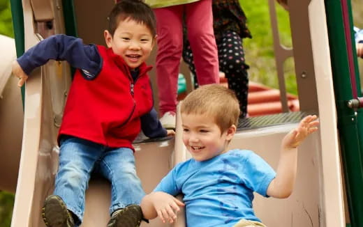 a couple of boys playing on a slide