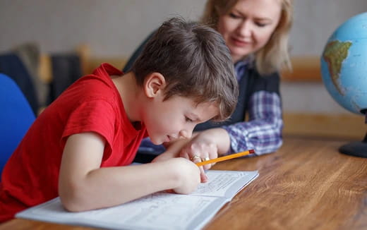 a boy and girl writing on a piece of paper
