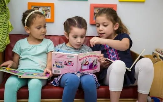 a group of children sitting on a bench reading books