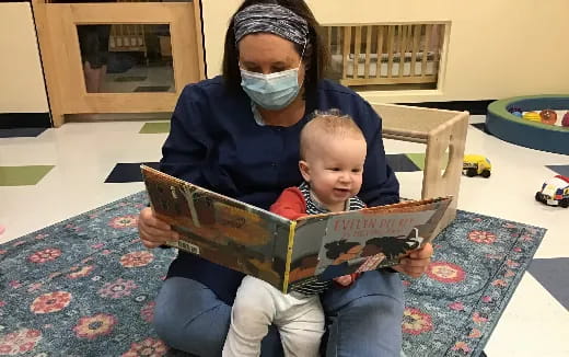 a person and a baby sitting in a box with a mask on