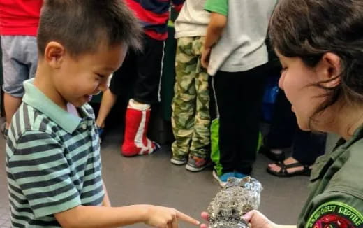 a person and a child looking at a rock