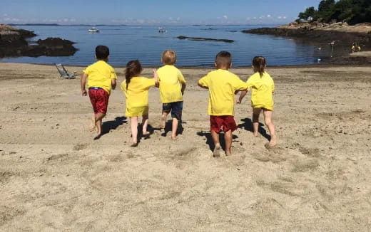 a group of children running on a beach