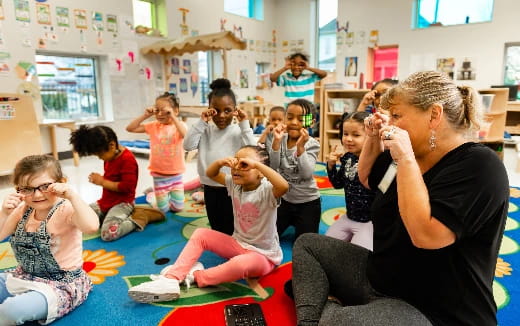 a person sitting on a rug with a group of children