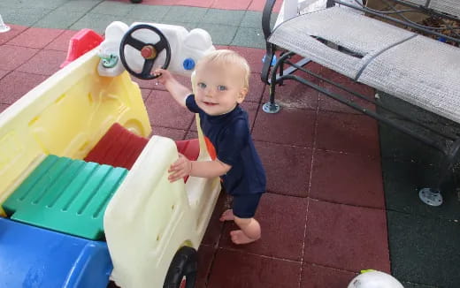a baby standing on a toy boat