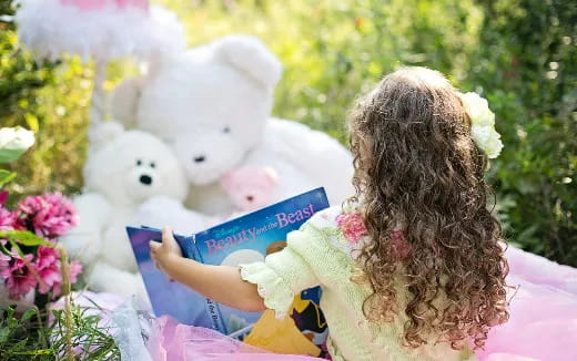 a person reading a book to a group of teddy bears