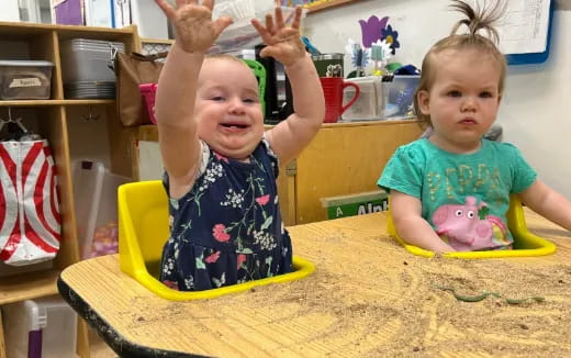 a couple of children sitting at a table with a toy
