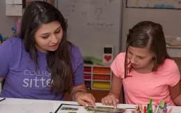 a woman and a girl looking at a book