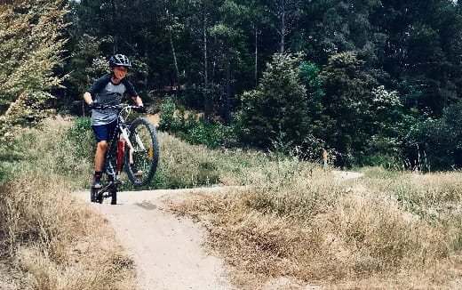 a boy riding a bike on a dirt road in the woods